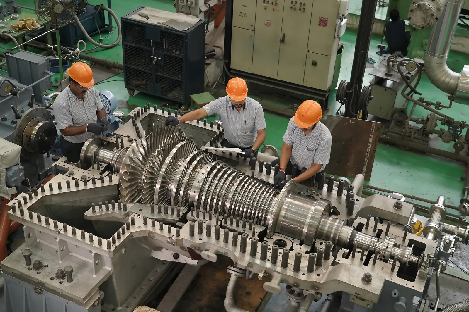 Technicians assembling an industrial gas turbine on the factory floor