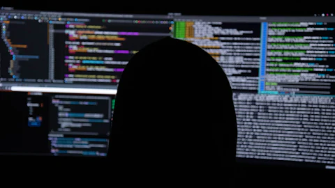 Analyst reviewing code across several monitors