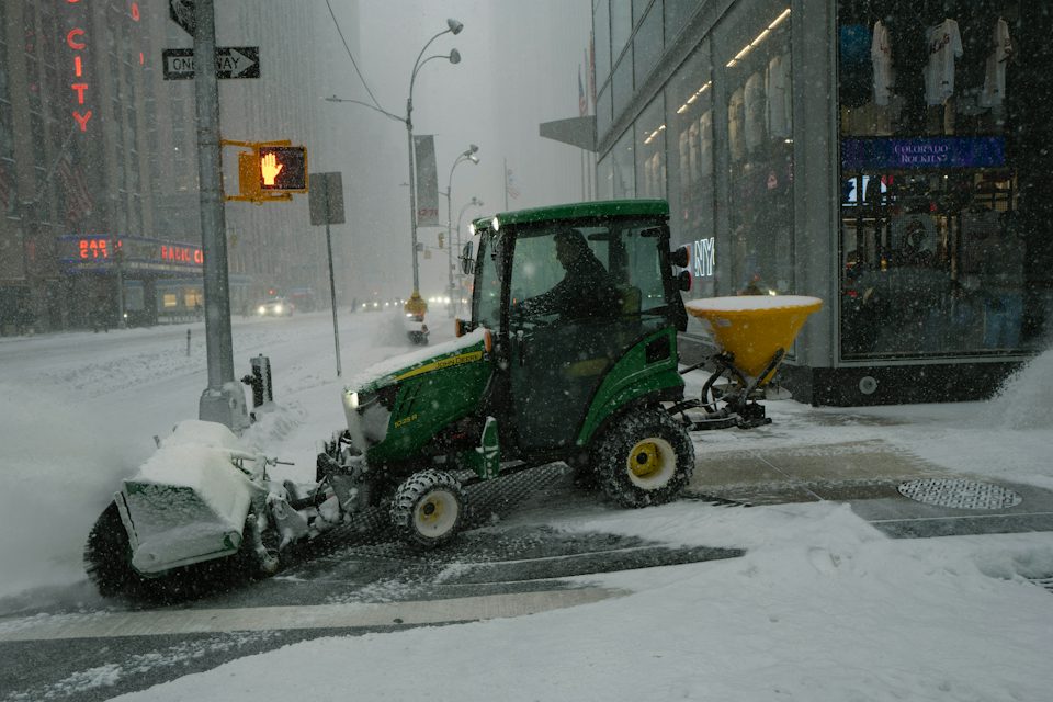 Plough and salt spreader clearing a city street