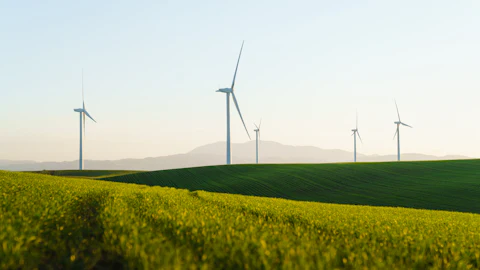 Wind turbines above green farmland